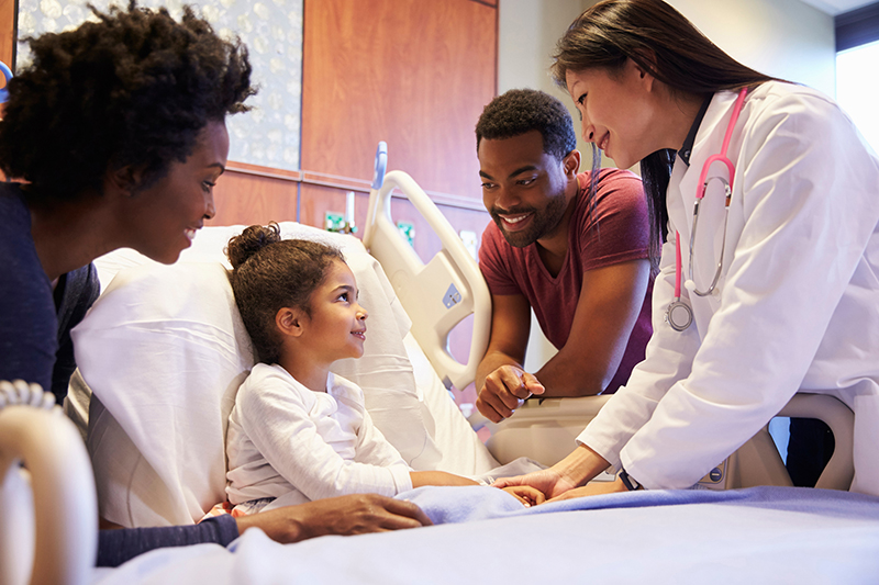 Girl in hospital bed with hospital staff