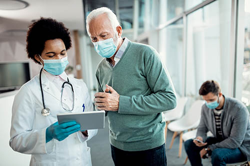 Nurse holding tablet talking to man